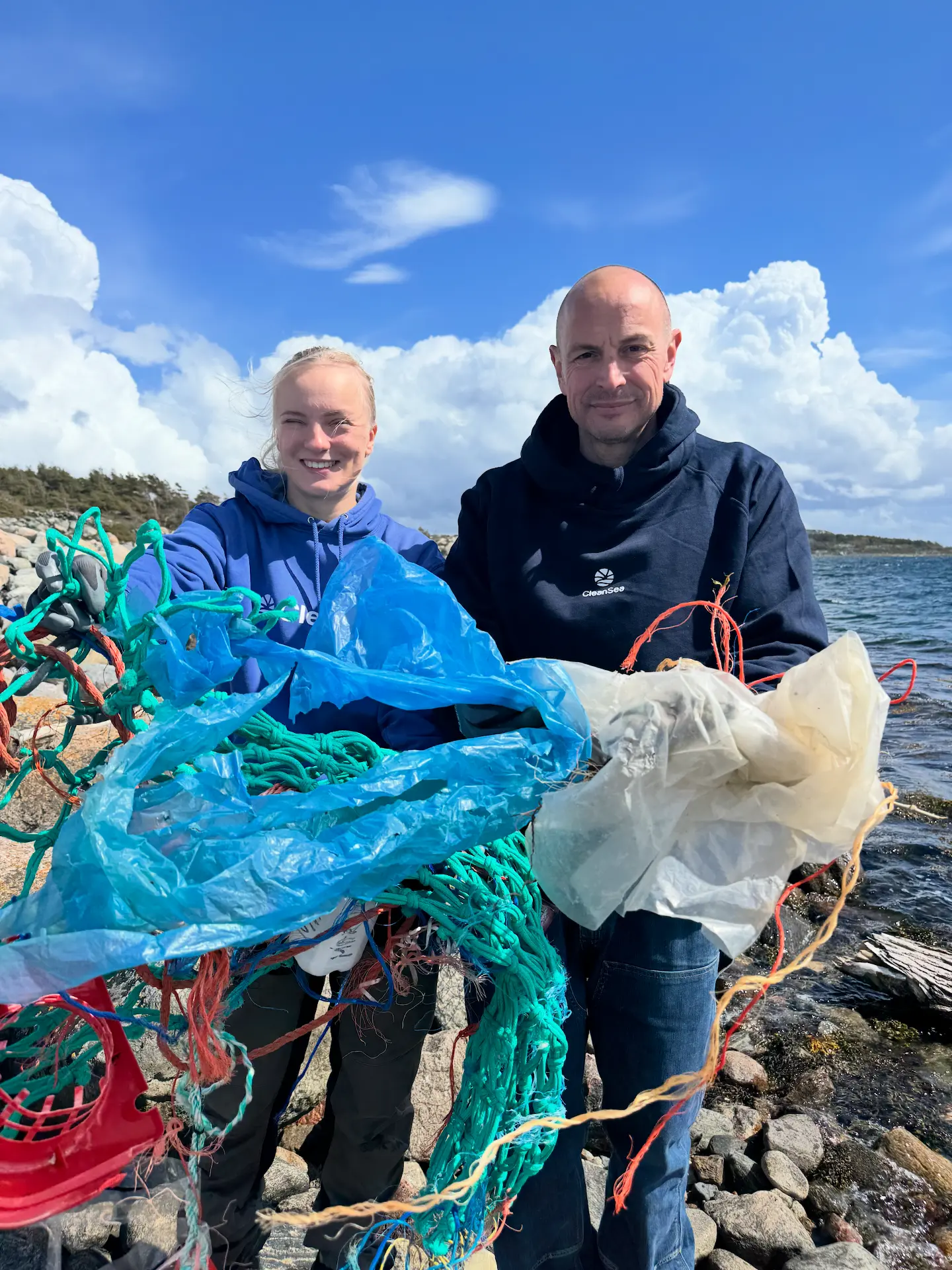 Förorenad stenig strand i skärgården med plastskräp bland klipporna